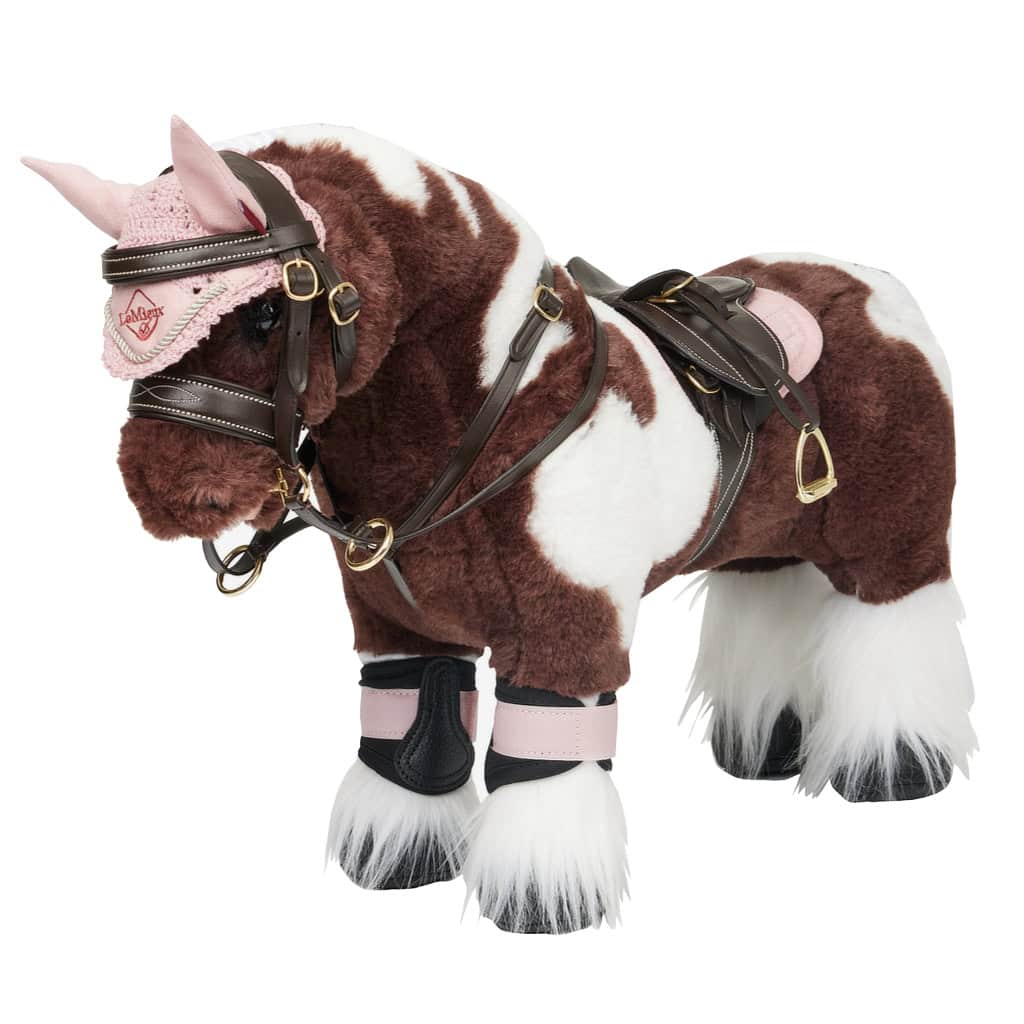 lemieux toy pony Dream, wearing brown saddle, bridle and martingale with pink quartz fly hood, saddle pad and grafter brushing boots